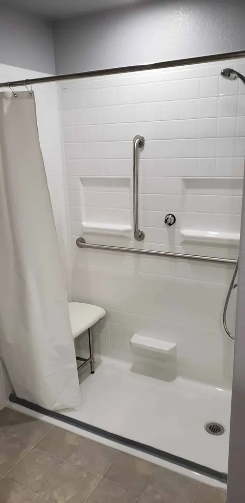 Wheelchair accessible roll in shower with fold up seat and built in accessories